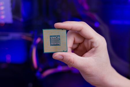 Back of a computer processor in hand. RGB light in background. Close-up.の写真素材