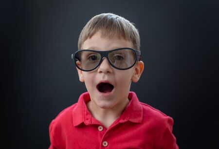 Boy with cinema 3d glasses with delighted face expression. Back background.の写真素材