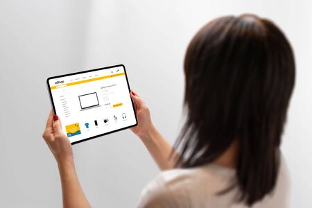 Woman holding tablet and shopping online. Flat design ecommerce web site on tablet display. Concept of buying technology products onlineの写真素材