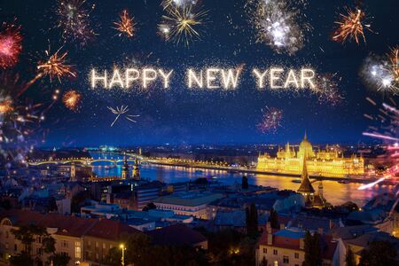 Happy New Year written with sparkle fireworks on night sky above Budapest surrounded by lots of fireworksの写真素材