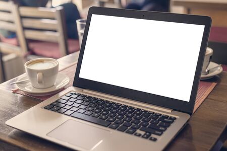 Laptop mockup on coffee shop desk. Cup of coffee beside. White screen for web page design presentationの写真素材