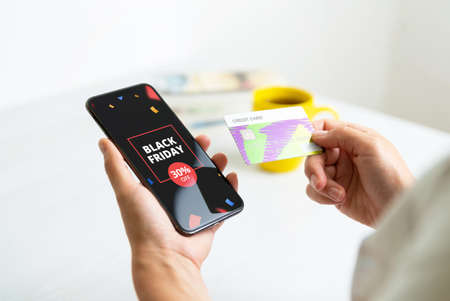 Black friday deal banner on smart phone. Woman holding credit card. Holiday online shopping conceptの写真素材