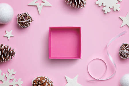 Open Christmas gift box on pink desk, surrounded by Christmas decorations. Concept of gift wrappingの写真素材