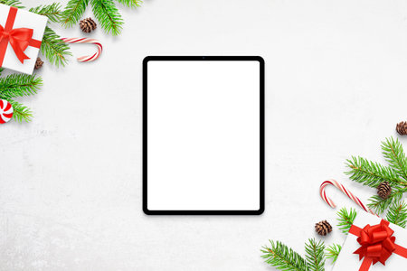 Tablet mockup on white desk with Christmas decorations. Top view, flat lay composition