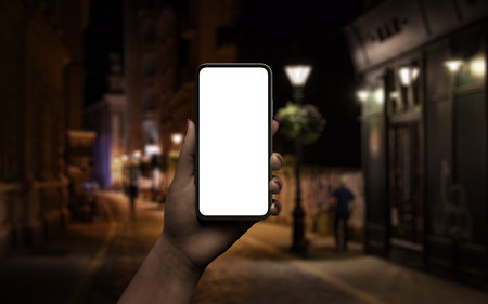 Phone mockup in woman hand. Night scene with city street in background