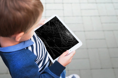 Broken tablet in boy hands concept. Smashed screen after dropの写真素材