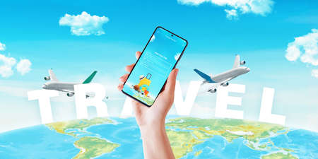 Hand with smart phone and trip plan app front of travel text on world map and planesの写真素材