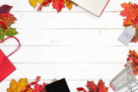Autumn shopping composition with bag, cart, pendant, chalk board and pad. Free space in the middle for sale text promotion. Top view, flat lay compositionの写真素材