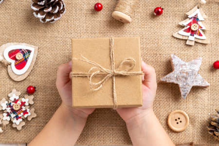 Children's hands hold a Christmas present just made. Table with Christmas decorations. Top view, flat lay compositionの写真素材