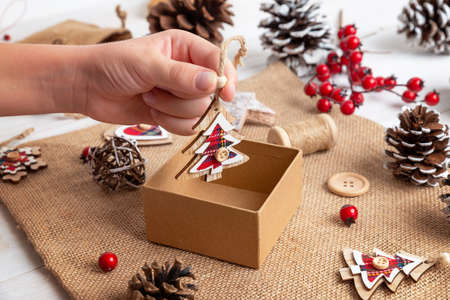 Kid hand drop a small decorative Christmas tree into the gift box. The concept of preparing Christmas presents and surprisesの写真素材