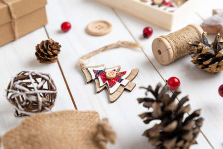 Wooden Christmas tree ornament with twine and button decoration surrounded by rustic Christmas decorationsの写真素材