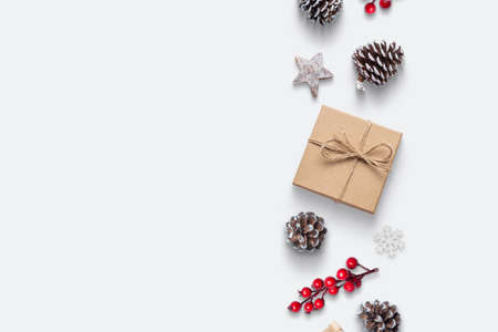 Christmas composition with copy space. Gift, pine cones, rose hip, snowflake and decorations in vertical line on white backgroundの写真素材