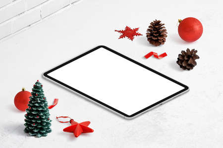 Tablet mockup on desk surrounded by Christmas decorations. Isolated display dor greeting text or web page promotion. Isometric viewの写真素材