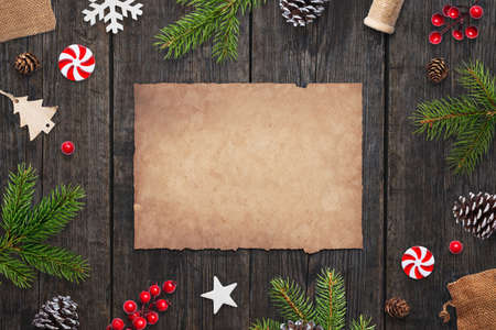 Clean aged paper for Christmas greeting text on wooden table with christmas decorations besideの写真素材