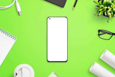 Phone mockup on greed work desk surrounded with office suplies, project papers, pens, plants, pad, coffee, plant. Isolated screen for mockupの写真素材