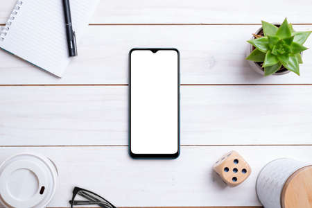 Phone mockup on white wooden work desk. top view composition. Isolated display for app design presentationの写真素材