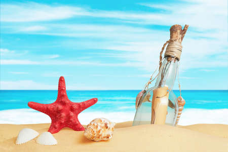 Star, shells and a message in a bottle on the beach sand. Summer tropical travel composition conceptの写真素材