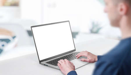 Mockup image of a man working at the laptop. Clean desk with office interior in background. Isolated screen in white for web page promotionの写真素材