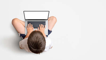 Boy sitting and working on a laptop. View from above. Isolated display for mockup, website promotion, app or game. Copy space besideの写真素材