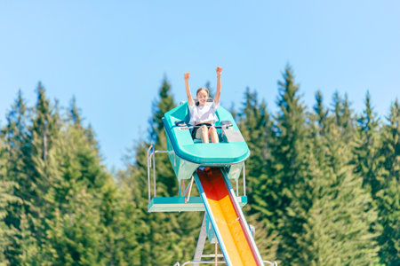 Nautic jet ride in mountain theme park. Girl are going down with outstretched armsの写真素材