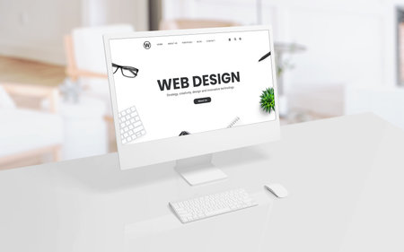 White computer display on an office or studio desk with a web design concept web page on the screen....