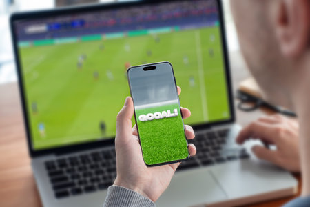 Guy watching football game on laptop and live score on smart phone concept
