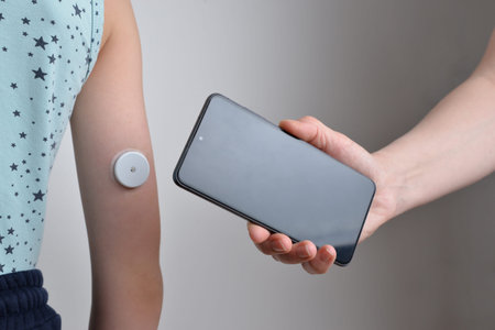 Reading blood sugar level with mobile phone and arm sensor. Concept of diabetes management, health...