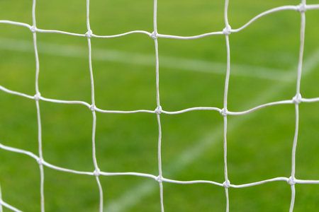 Close-up shot of a goal net with green grass and field lines in the background