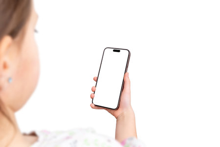 Over the shoulder view of a young girl holding a modern smartphone, isolated background and screen, ideal for app promotion or digital interactionの写真素材