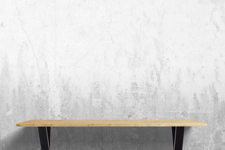 Rustic oak wood desk with black metal legs, set against a textured white wall with aged details, blending modern workspace aesthetics with industrial charmの写真素材