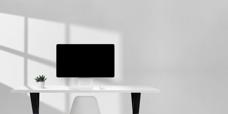 Bright office desk with computer monitor, keyboard, mouse, and plant, clean workspace with empty space on the right for copy or brandingの写真素材