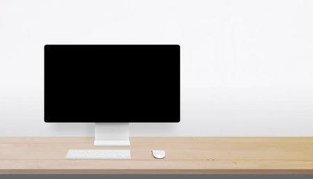 Minimalist desktop setup with wooden surface, blank monitor, and wide open space on the right for branding, advertising, or creative messagingの写真素材