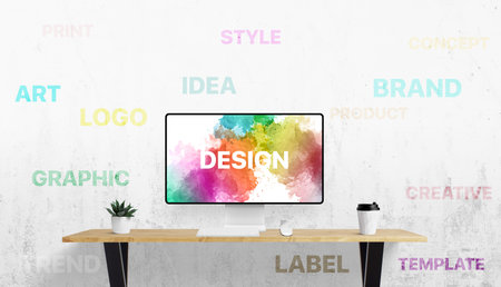 Office setup with digital screen and white wall filled with design-related terms like idea, logo, brand, and art â a visual language of creativityの写真素材