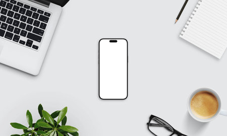 Smartphone mockup on light desk surrounded by laptop, notebook, coffee, glasses, and plant. Perfect for app design and digital brandingの写真素材