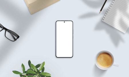 Smartphone mockup on soft-lit desk with coffee, glasses, notebook, and shadows. Perfect for natural presentation of apps and digital contentの写真素材
