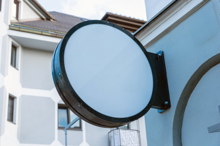 Blank circular signage on exterior wall, ready for custom logo, storefront branding or commercial display presentation in daylight environmentの写真素材