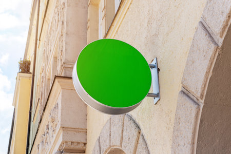 Round green signboard mockup on stone wall in bright daylight, perfect for branding, identity, logo or storefront promotionの写真素材
