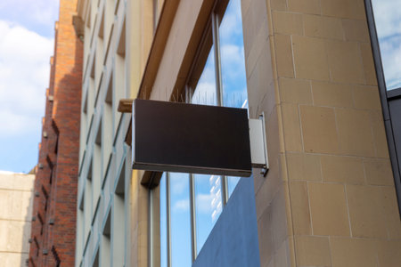 Black rectangular store sign with bird spikes on top, ideal for urban branding mockups, commercial signage or corporate advertising visualsの写真素材