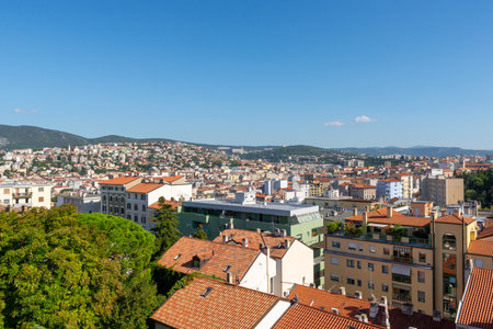 Trieste, Italy â September 26 2023: Cityscape view with terracotta rooftops and surrounding hills under a clear blue skyの写真素材
