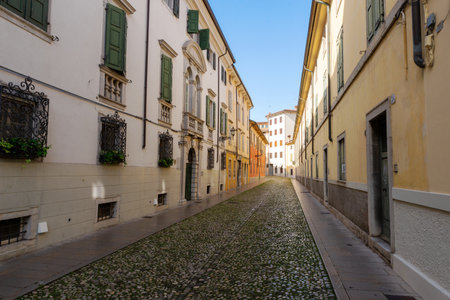 Quiet cobblestone street in Udine with colorful historic buildings and shuttered windowsの写真素材
