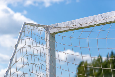 Close-up of white wooden football goal with attached net against clear blue sky.の写真素材
