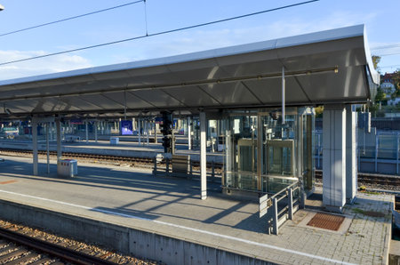 Modern train station platform with glass elevator and shelter roof.の写真素材