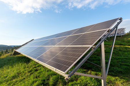 Large solar panel installation on green hillside generating renewable electricity in bright morning sunlightの写真素材
