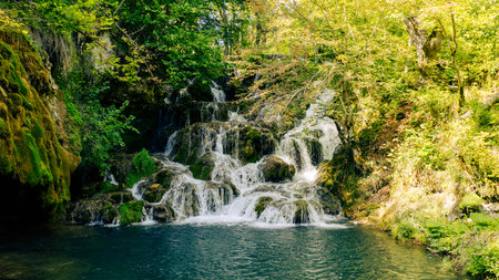Small cascading waterfall surrounded by moss and trees in pristine forest nature
