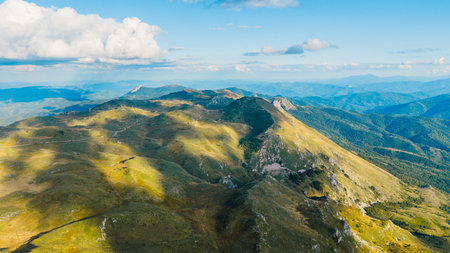 Bright mountain ridges and hills illuminated by sunlight in panoramic drone viewの写真素材