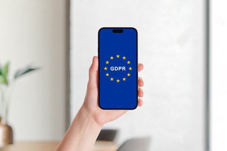 Hand holding smartphone displaying European Union flag and GDPR logo symbolizing data protection, privacy rights, and European digital regulationsの写真素材