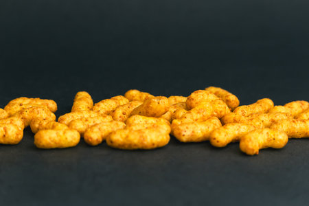 Crispy peanut puff snacks on dark background, crunchy salty bites perfect for fast food advertising, packaging, and snack product designの写真素材