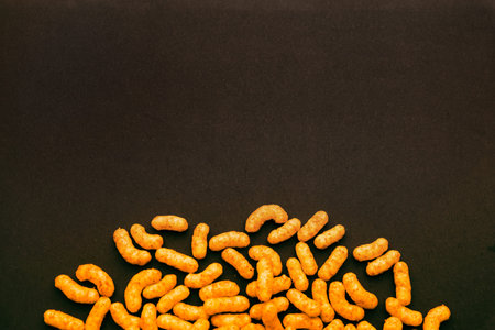Peanut puff snacks on dark surface with empty copy space, minimalist food background perfect for...