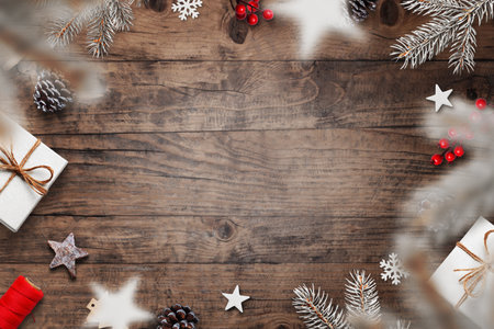 Festive Christmas flat lay with frosty pine branches, snowflakes, gifts and red berries on wooden background, top view winter decorationの写真素材