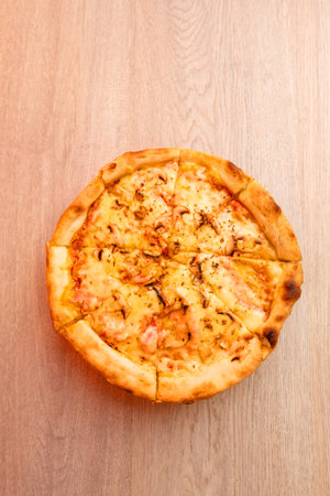 Close-up of a freshly baked pizza with melted cheese and mushrooms on a wooden table, viewed from above, isolated and ready to serveの写真素材